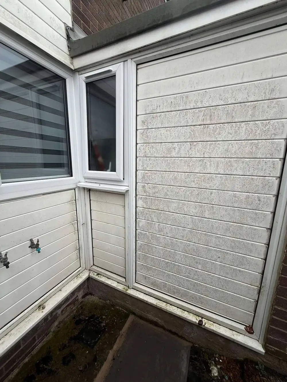 Dirty, algae-stained white uPVC cladding before cleaning