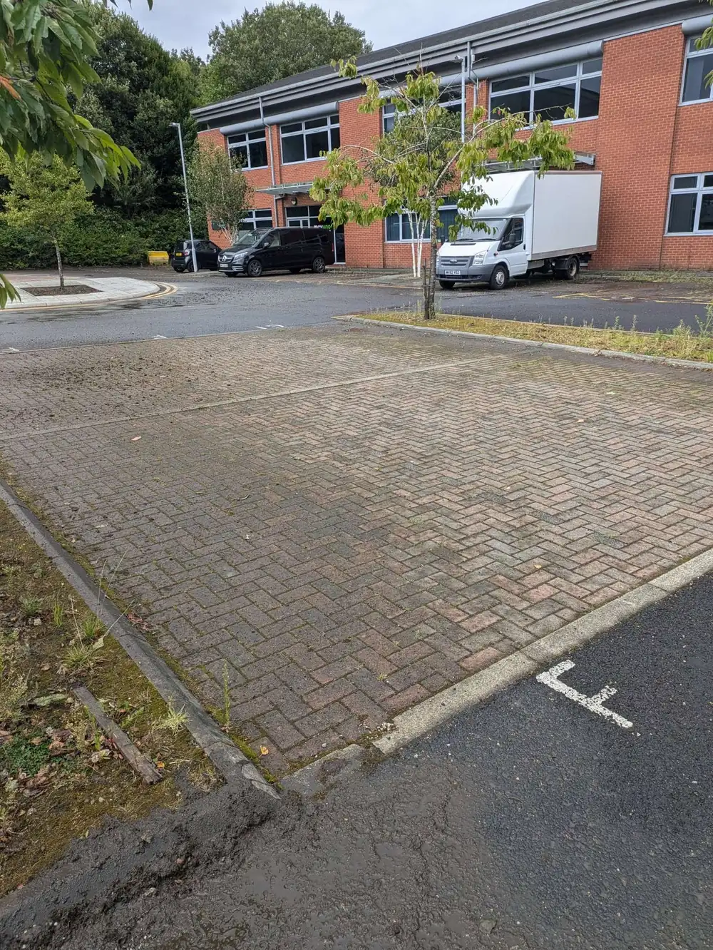 Weedy office car park block paving before cleaning
