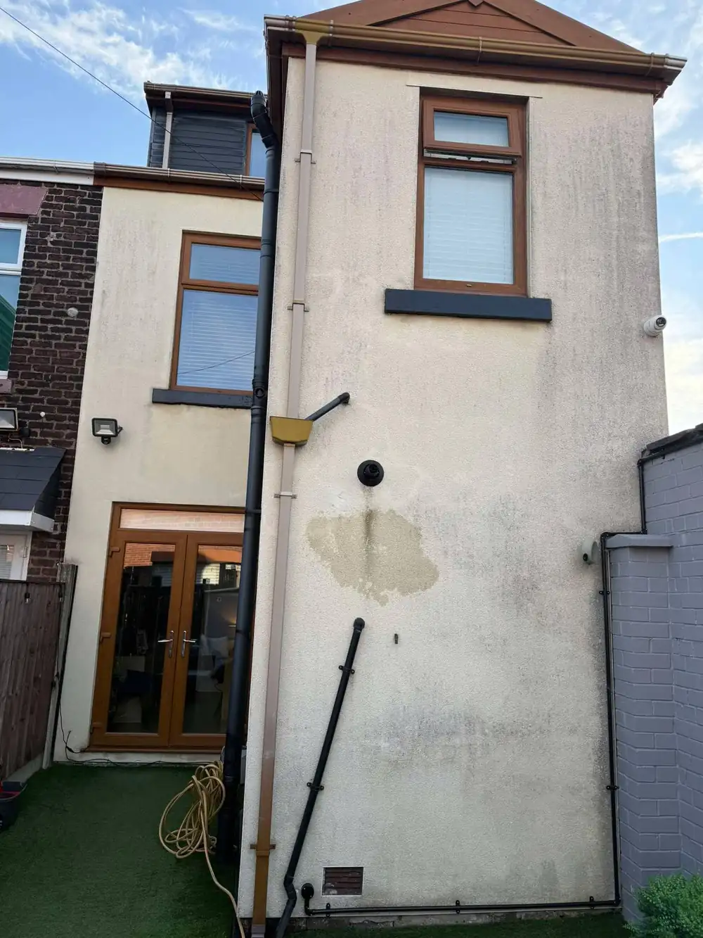 Rendered gable streaked with green algae before cleaning