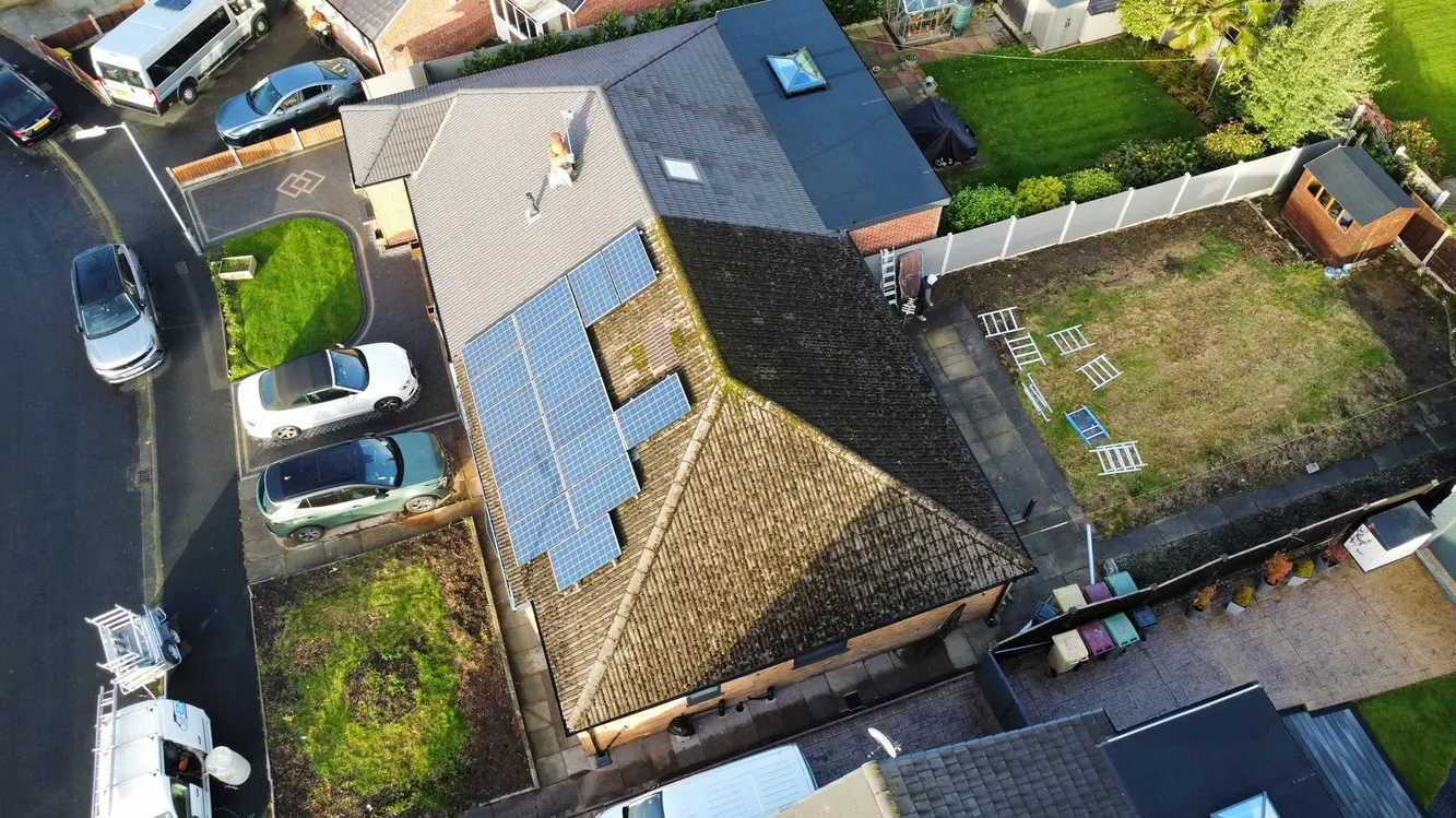 Drone view of a mossy roof with solar panels before cleaning