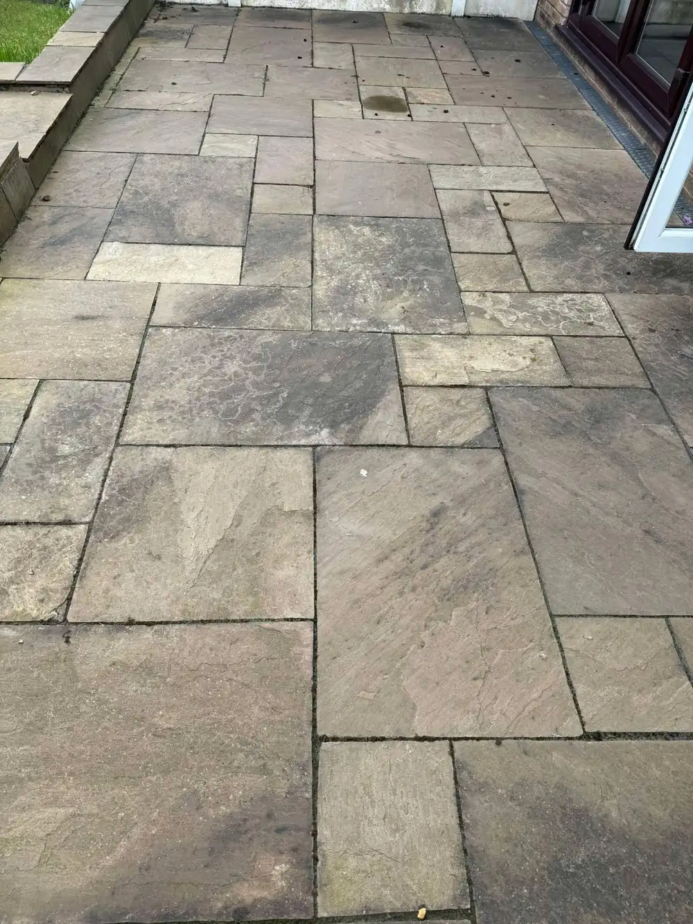 Dull, weathered autumn-blend sandstone patio before cleaning