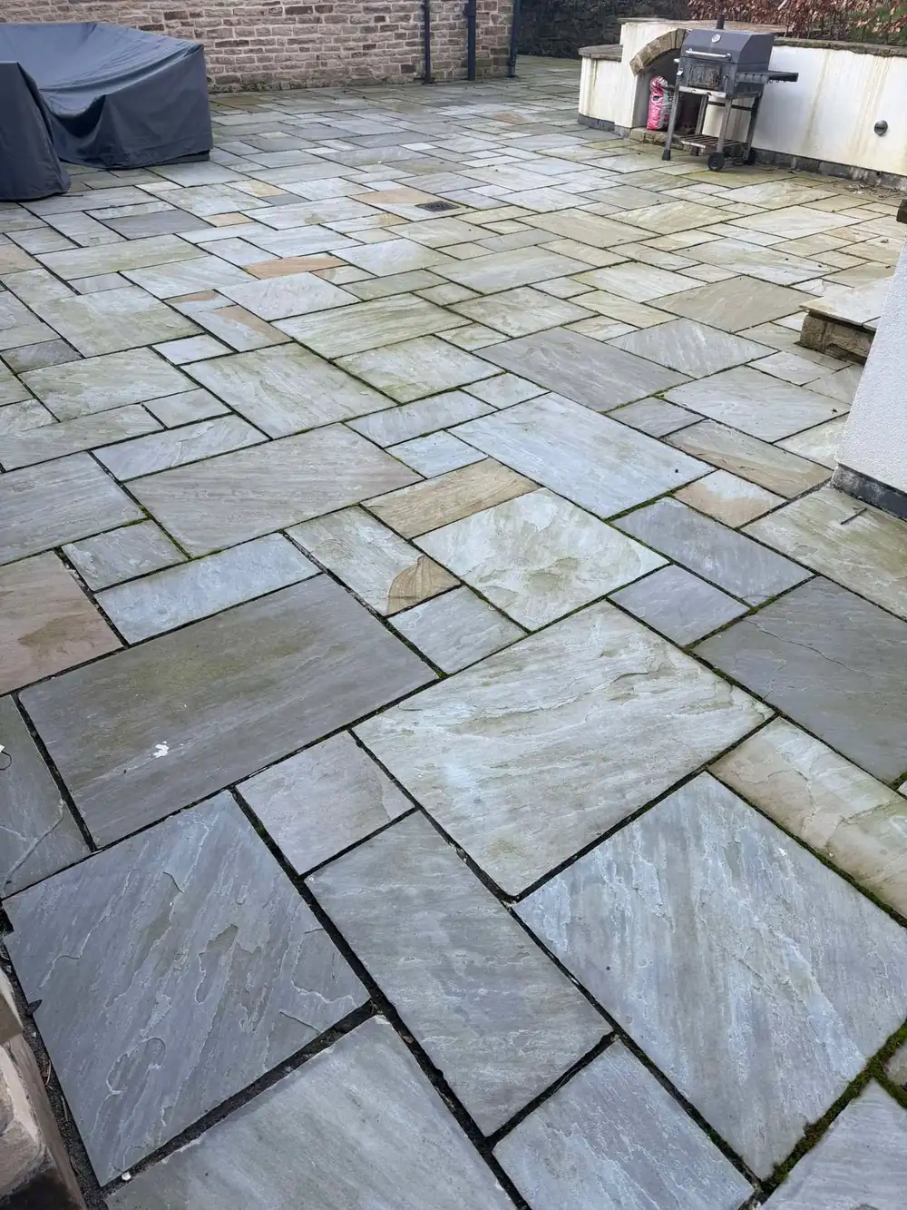 Grey, weathered Indian sandstone patio before cleaning