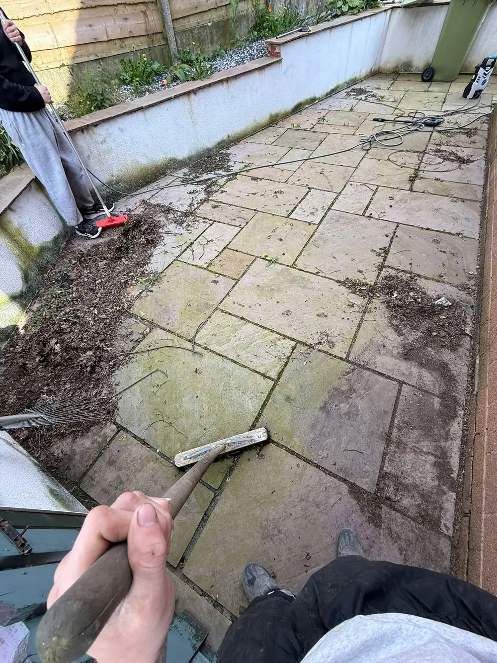 Dirty grey sandstone patio with moss before cleaning
