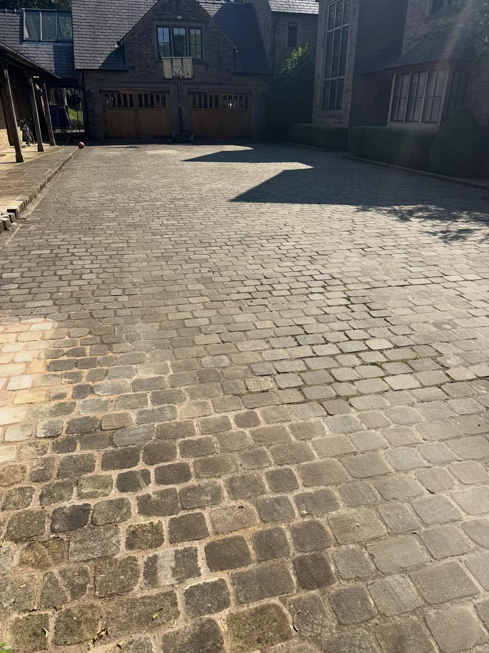 Dark, grimy cobble sett driveway before cleaning