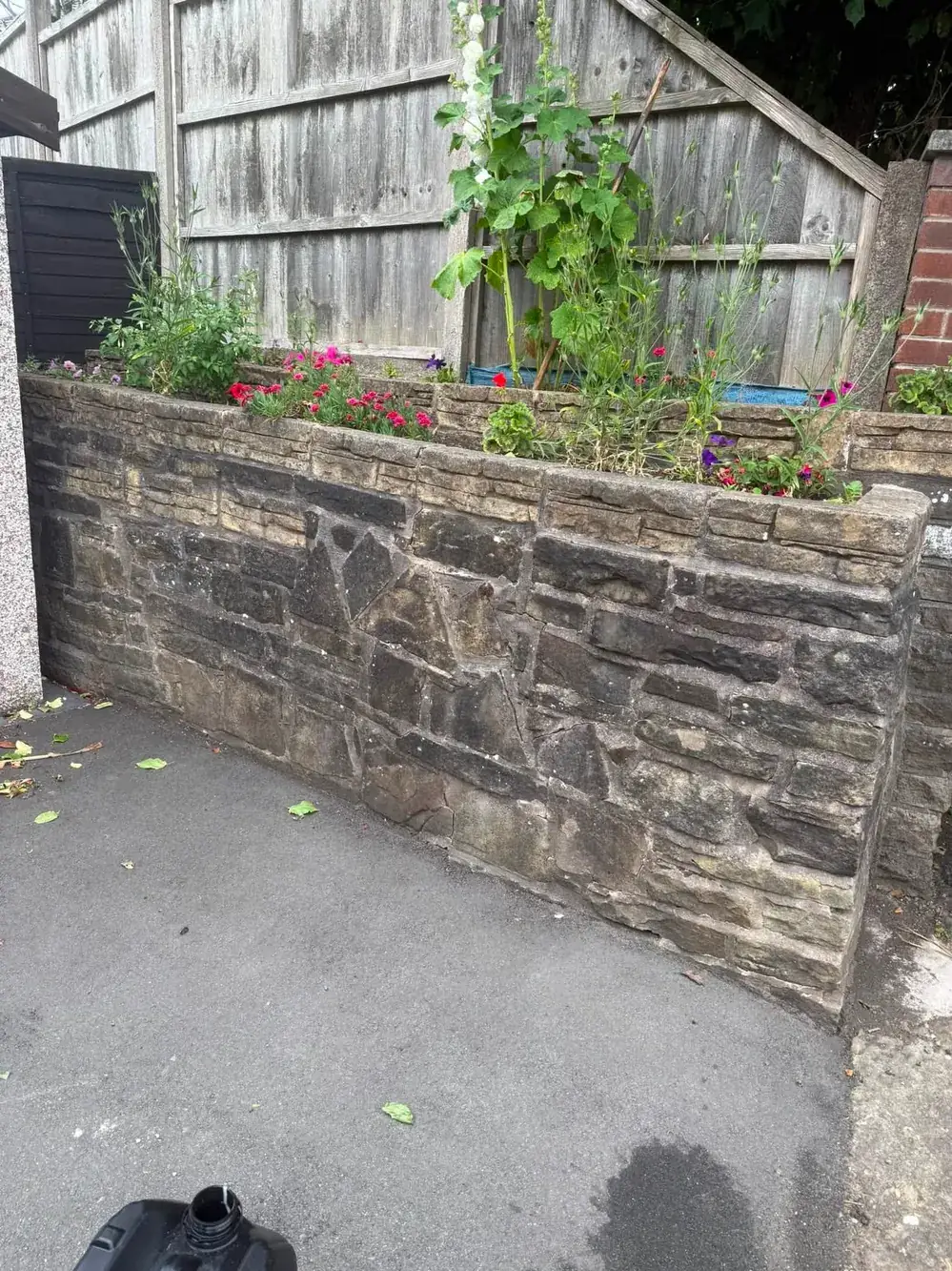 Dark, weathered sandstone garden wall before cleaning