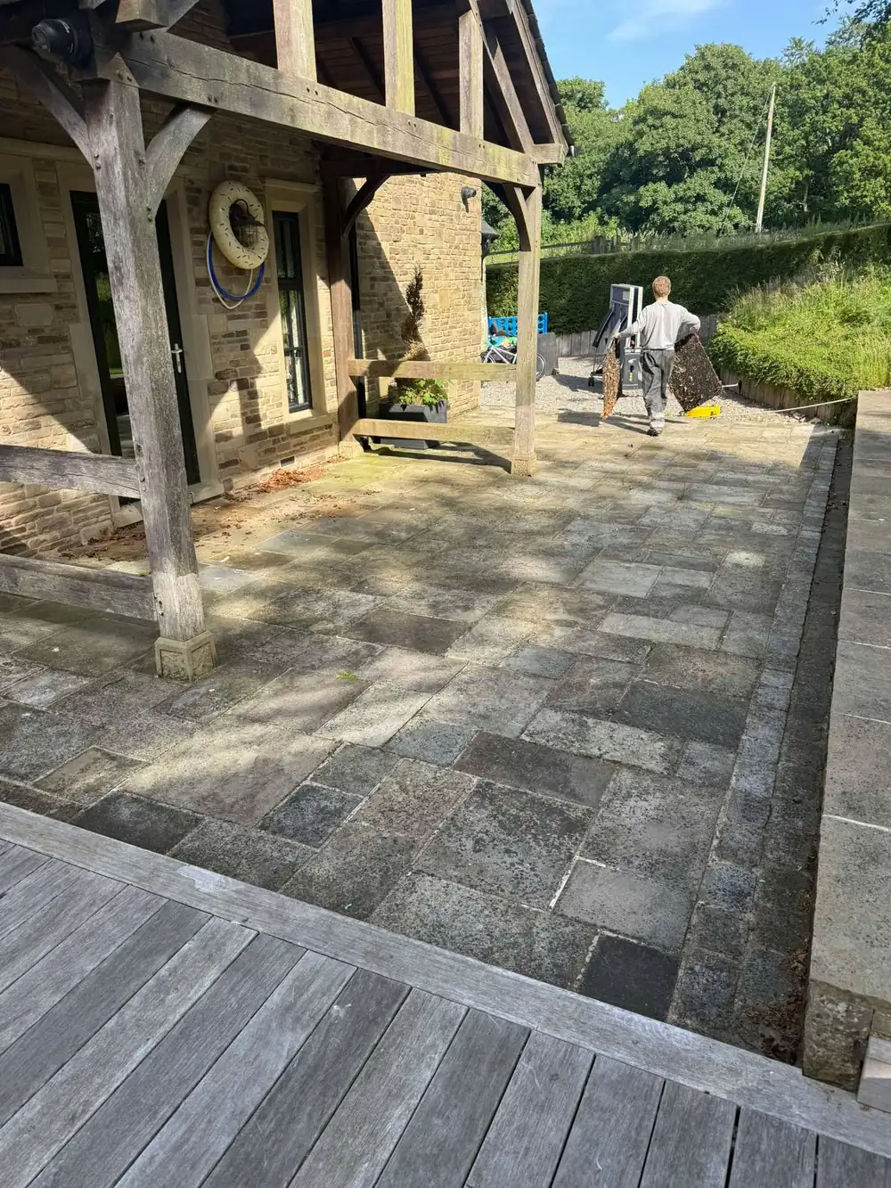 Grey, dirty natural stone flags under a pergola before cleaning