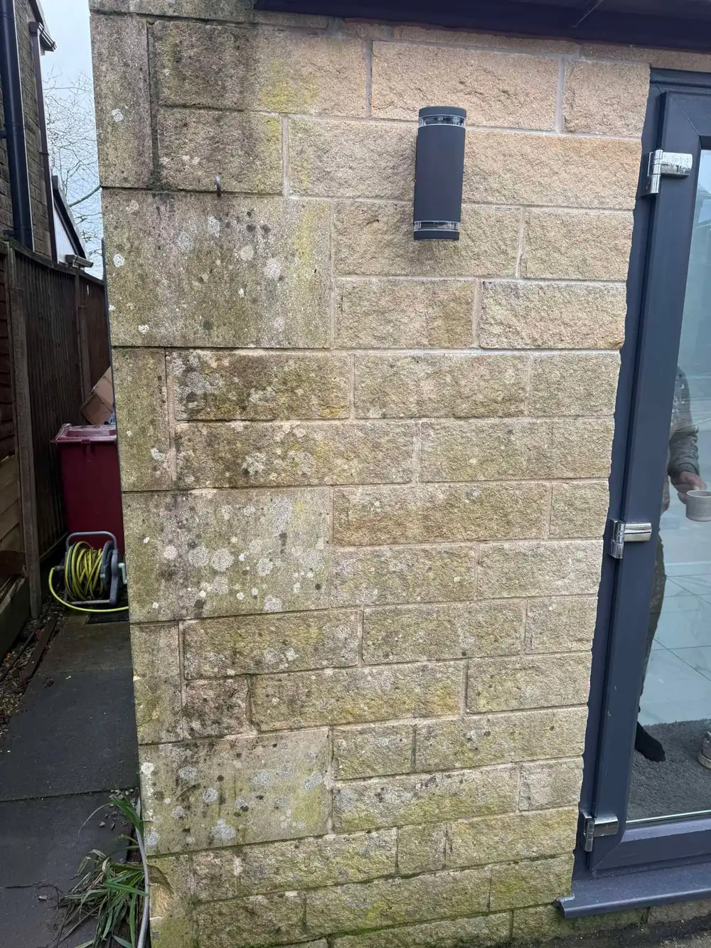 Lichen-covered stone wall and pillar before cleaning