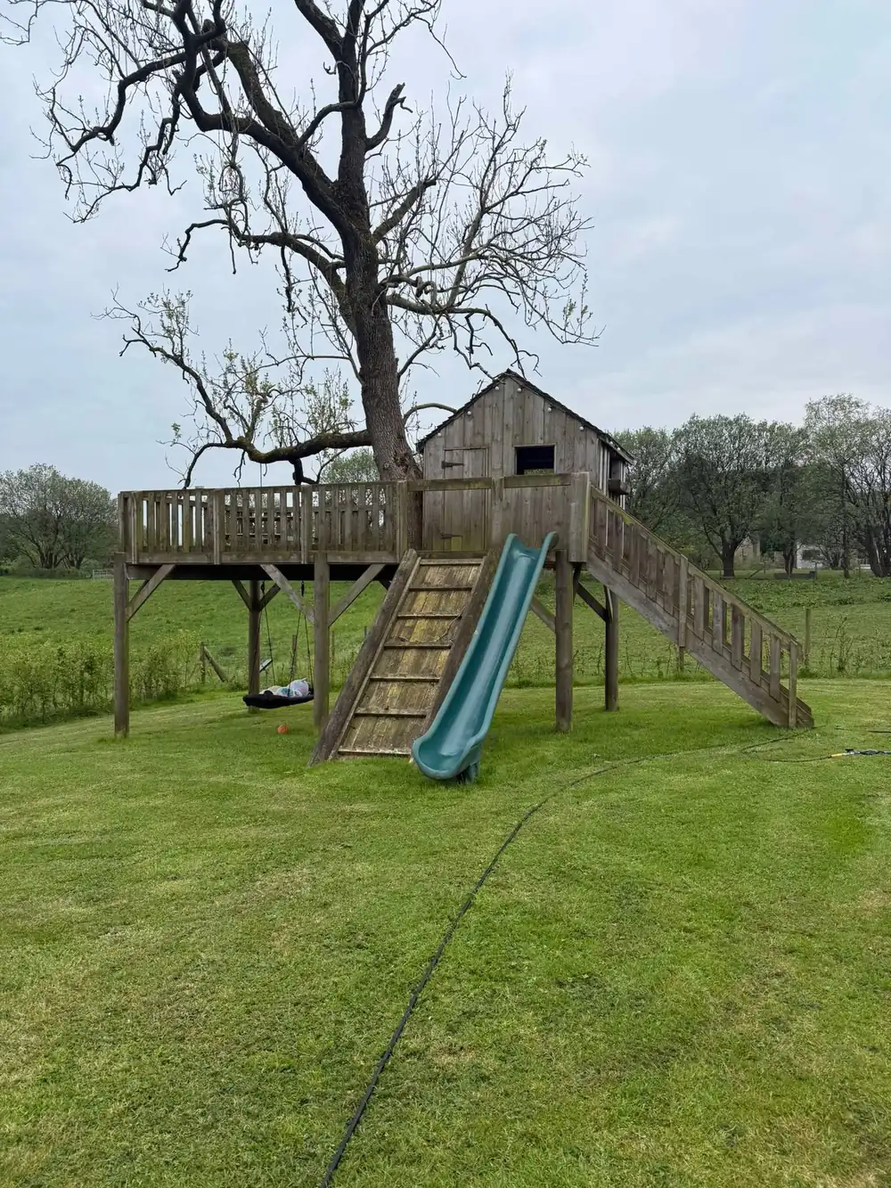 Weathered timber play tower and slide before cleaning